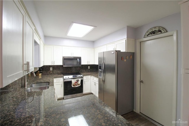 kitchen with dark stone counters, a sink, decorative backsplash, appliances with stainless steel finishes, and white cabinetry