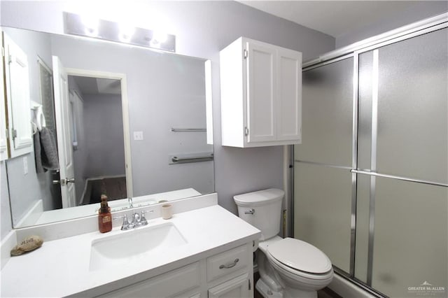 bathroom with vanity, a shower stall, and toilet