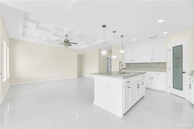 kitchen featuring white cabinets, decorative backsplash, sink, and a kitchen island with sink