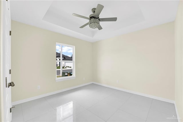 spare room with ceiling fan, light tile patterned flooring, and a raised ceiling