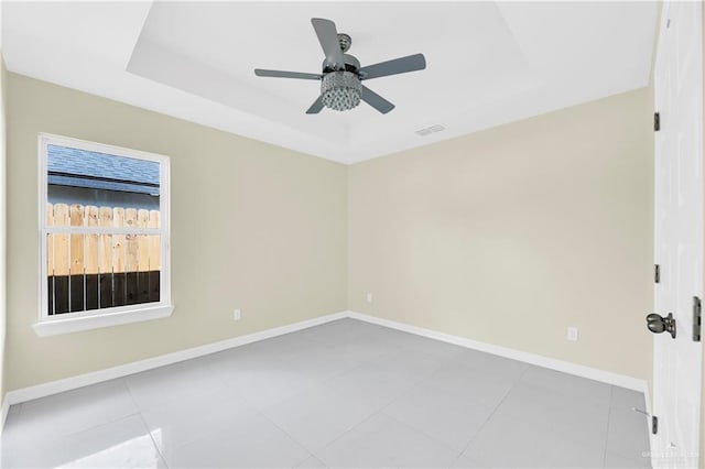 tiled spare room featuring a tray ceiling and ceiling fan