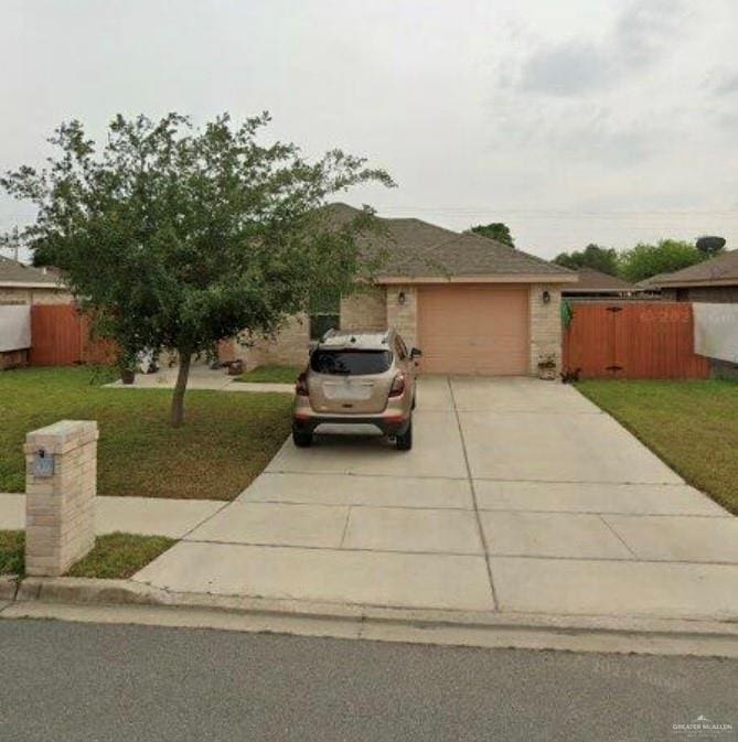 view of front of house featuring driveway, an attached garage, a front yard, and fence