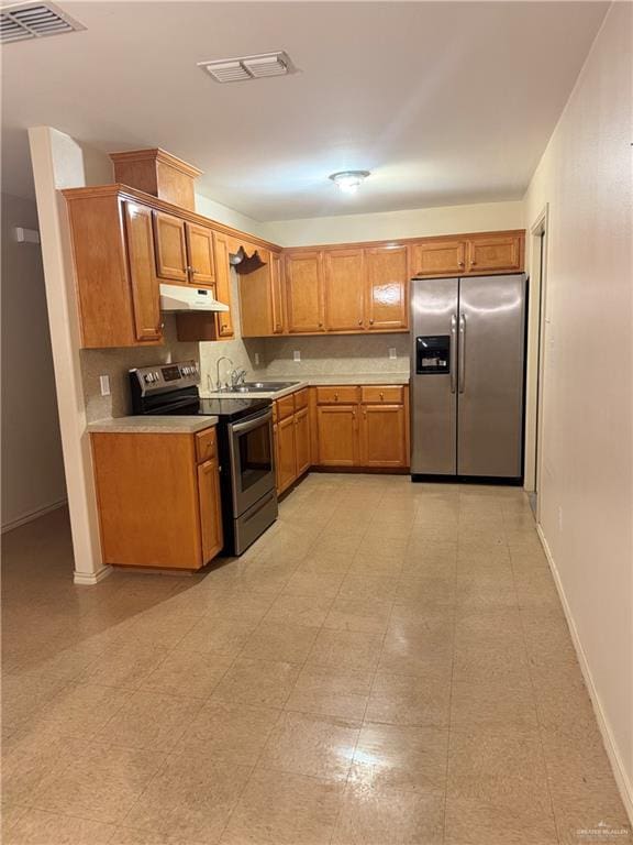 3013 Ozark Ave, Mcallen, TX 78504 - kitchen with stainless steel appliances, under cabinet range hood, light countertops, brown cabinets, and baseboards