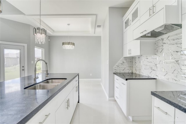 kitchen with backsplash, a raised ceiling, sink, pendant lighting, and white cabinetry