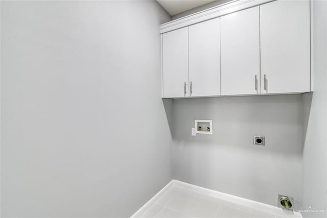 clothes washing area with hookup for an electric dryer, hookup for a washing machine, tile patterned floors, and cabinets