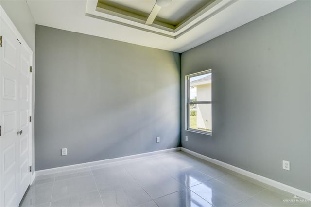 tiled spare room with a raised ceiling