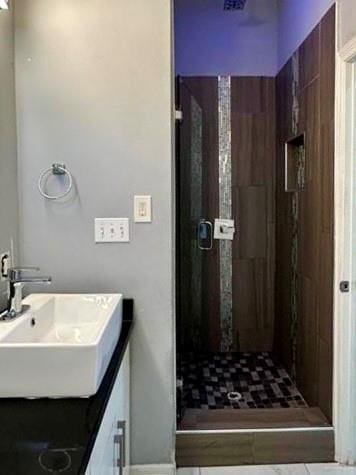 bathroom with a stall shower and a sink