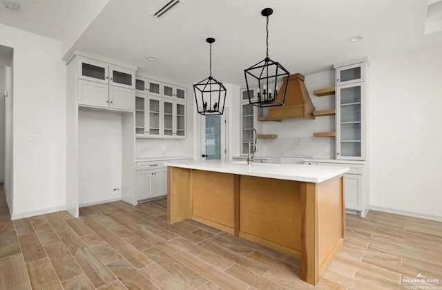 2080 Eagle Landing Dr, Edinburg, TX 78542 - kitchen with open shelves, light wood-style floors, a center island with sink, white cabinetry, and light countertops