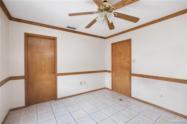 spare room with ceiling fan, ornamental molding, and light tile patterned floors