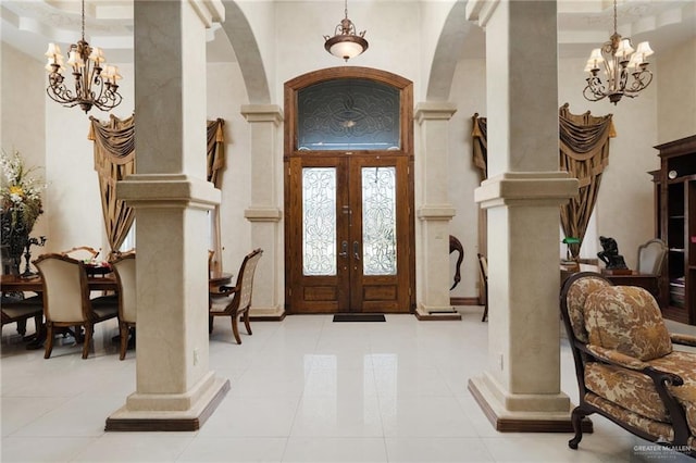 foyer with an inviting chandelier, decorative columns, arched walkways, and a high ceiling