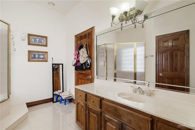 full bathroom featuring vanity, baseboards, tile patterned floors, a stall shower, and a notable chandelier
