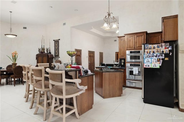 kitchen with a warming drawer, double oven, a kitchen island, dark countertops, and freestanding refrigerator