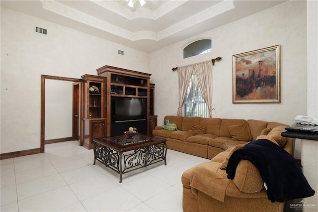 living area with baseboards, light tile patterned flooring, a towering ceiling, visible vents, and a ceiling fan