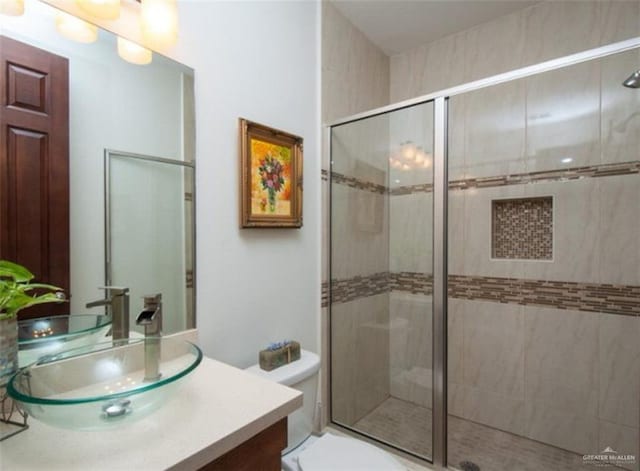 bathroom featuring vanity, toilet, and a shower with door