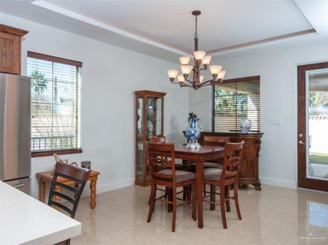 dining room featuring a notable chandelier, plenty of natural light, and a tray ceiling