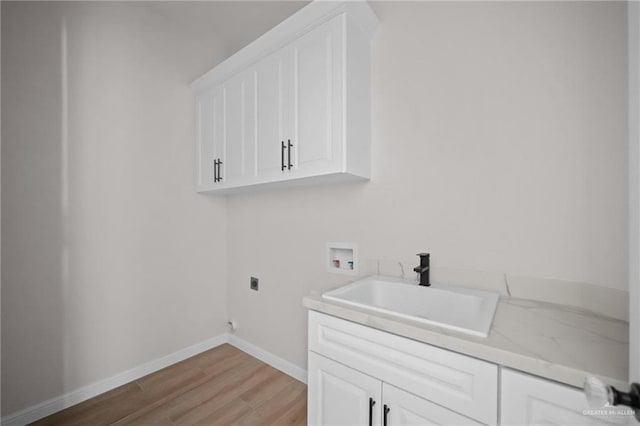 laundry area with electric dryer hookup, cabinets, sink, washer hookup, and light wood-type flooring