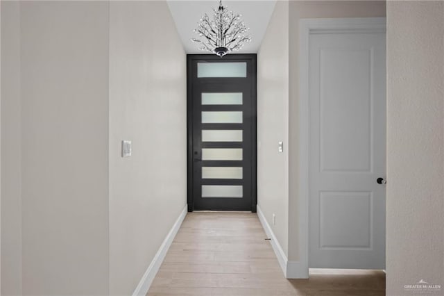 doorway to outside featuring light hardwood / wood-style flooring and a notable chandelier