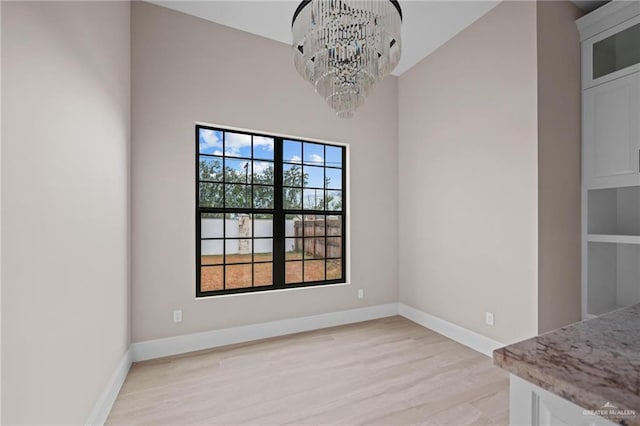 unfurnished dining area featuring light hardwood / wood-style floors and a notable chandelier