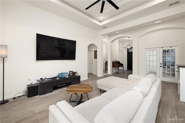 living room featuring french doors, ceiling fan, a tray ceiling, and hardwood / wood-style floors