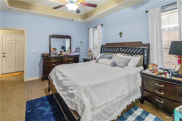 bedroom with tile patterned floors, a raised ceiling, and ceiling fan