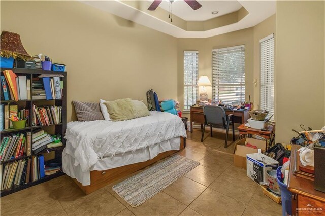 tiled bedroom with a raised ceiling and ceiling fan