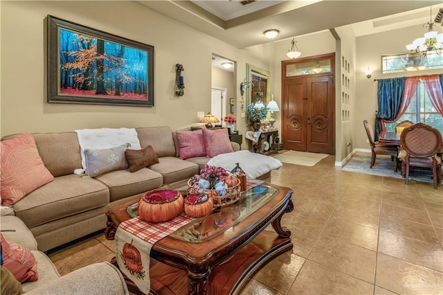 living room featuring light tile patterned floors, a tray ceiling, and an inviting chandelier