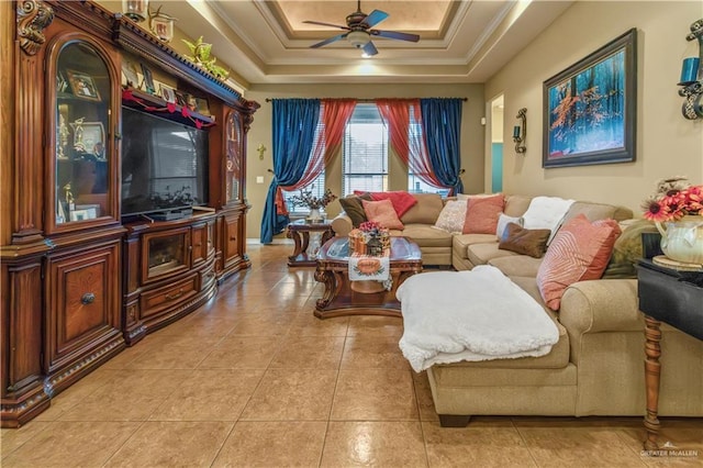 tiled living room featuring ceiling fan, a raised ceiling, and ornamental molding