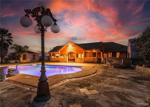 pool at dusk with a patio area