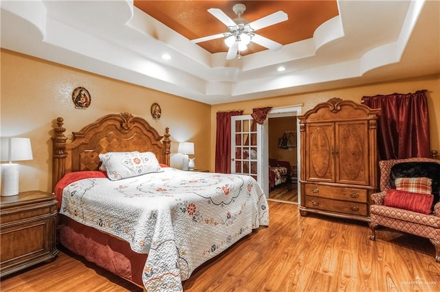 bedroom featuring a tray ceiling, light hardwood / wood-style flooring, and ceiling fan