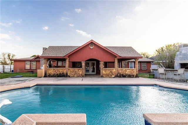 view of swimming pool with french doors, an outdoor fireplace, an outdoor bar, and a patio