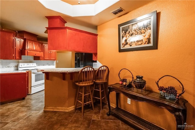 kitchen with black refrigerator, kitchen peninsula, white range with electric stovetop, and decorative backsplash