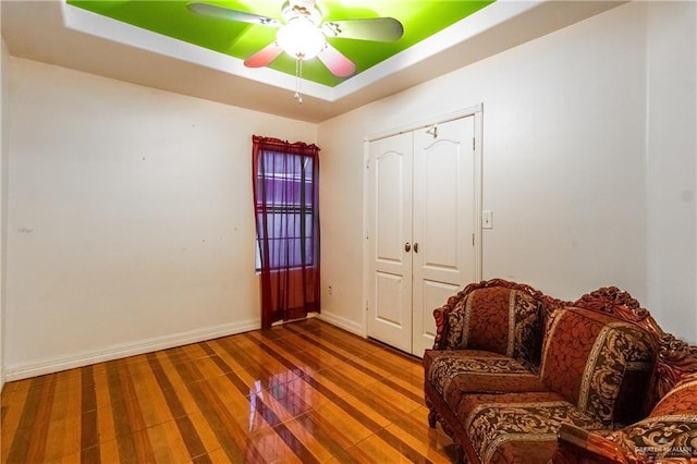 sitting room with a raised ceiling and ceiling fan