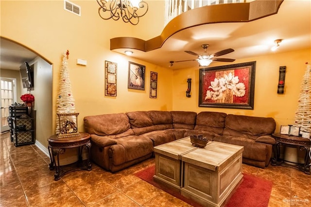 living room featuring dark tile patterned floors, ceiling fan, and a towering ceiling