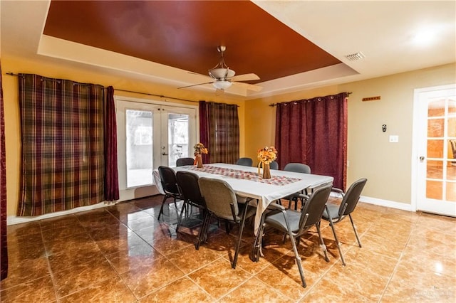 dining area featuring a raised ceiling, ceiling fan, and french doors