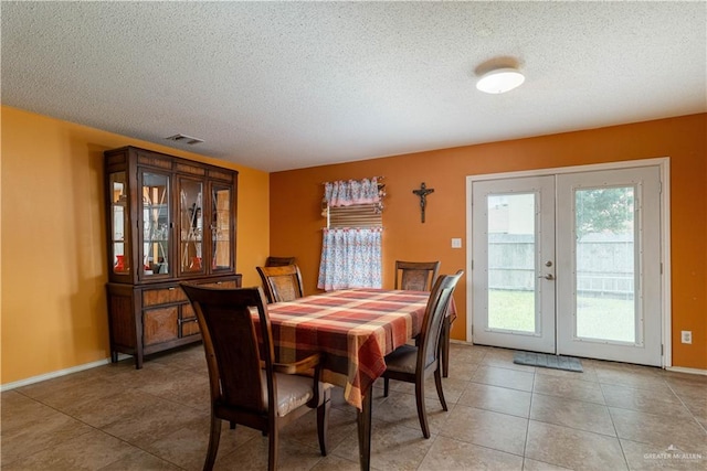 tiled dining room featuring a textured ceiling and french doors