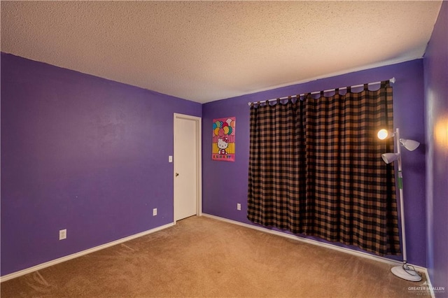 carpeted empty room featuring a textured ceiling