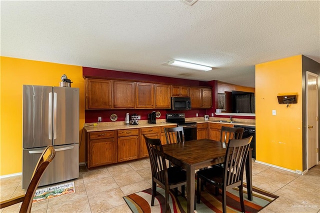 kitchen with light tile patterned flooring, a textured ceiling, sink, and black appliances