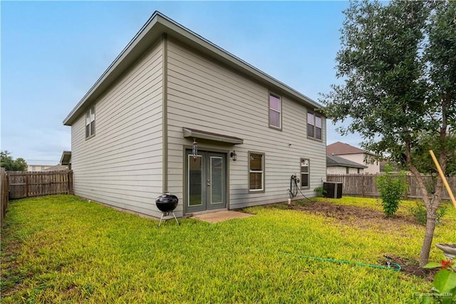 rear view of house featuring french doors, a lawn, and central air condition unit