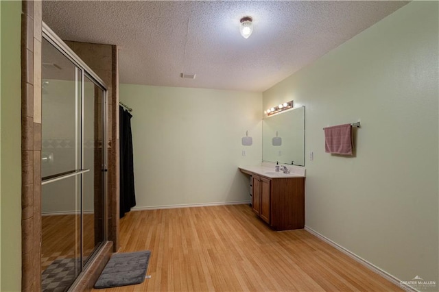 bathroom featuring hardwood / wood-style floors, a shower with shower door, and a textured ceiling