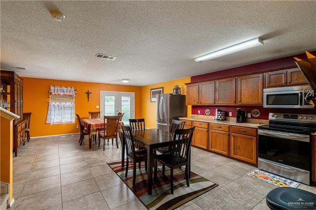 kitchen featuring light tile patterned floors, stainless steel appliances, and a textured ceiling