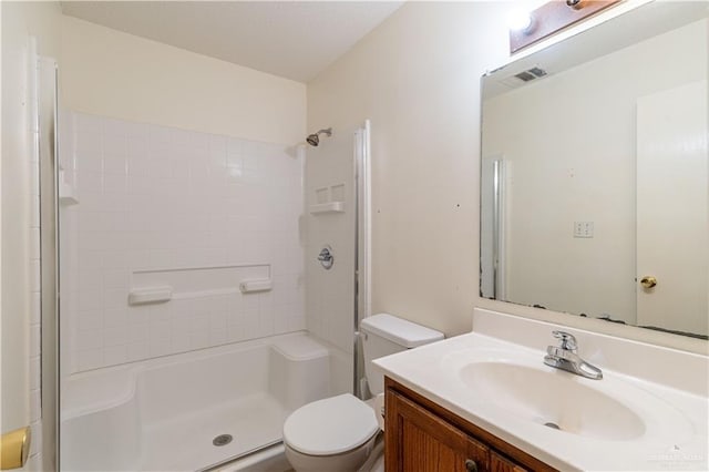 bathroom with a tile shower, vanity, and toilet