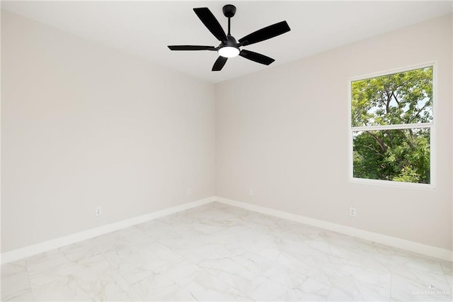 spare room featuring baseboards, marble finish floor, ceiling fan, and a wealth of natural light
