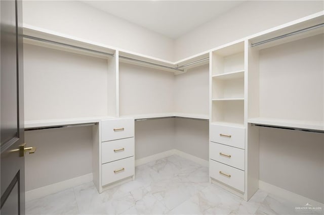 spacious closet with built in desk and marble finish floor