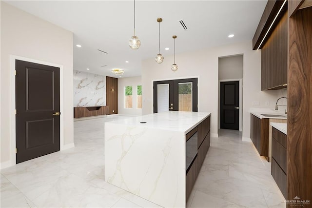 kitchen featuring a sink, french doors, marble finish floor, a large island, and modern cabinets