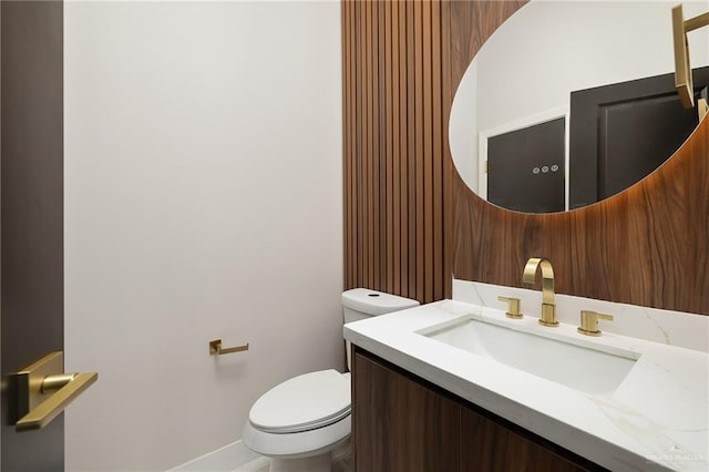 bathroom with toilet, baseboards, and vanity