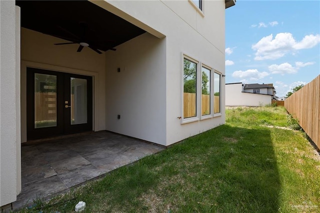 exterior space with fence, stucco siding, french doors, a ceiling fan, and a yard