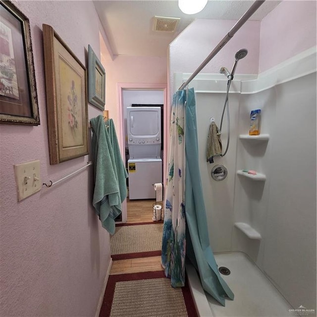 16073 S US Highway 281, San Benito, TX 78586 - bathroom with stacked washer / dryer, a shower with curtain, baseboards, and wood finished floors