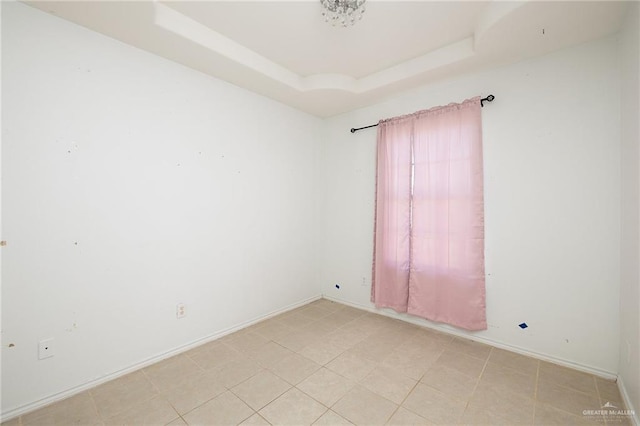 tiled spare room with a raised ceiling