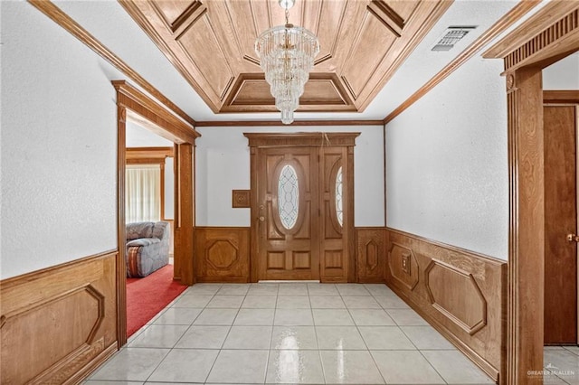 entrance foyer featuring a raised ceiling, crown molding, light tile patterned flooring, and an inviting chandelier