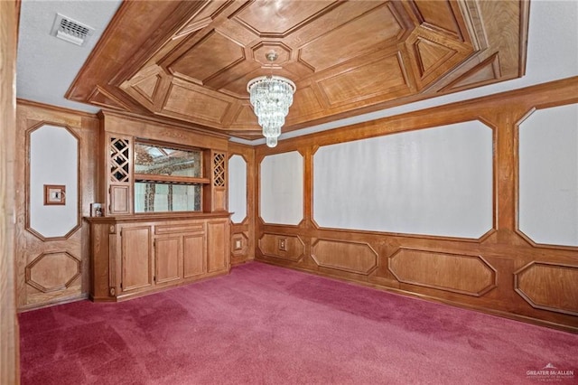 spare room with carpet flooring, wooden walls, and an inviting chandelier